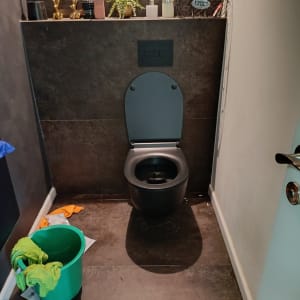 אסלה עם דלי ירוק ומטלית בחדר שירותים