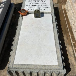 מצבת שיש עם מסגרת אבן ובית נר מותקן בבית עלמין