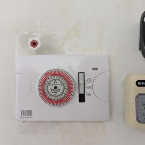 טיימר חשמלי על קיר עם כפתור הפעלה