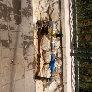 צנרת מים מותקנת על קיר אבן חיצוני