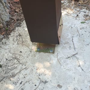 עמוד עץ חום מחובר לבסיס מתכת על בטון