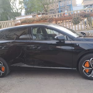 מכונית שחורה עם גלגלים בעיצוב ייחודי וחישוקי בלמים כתומים