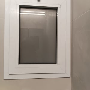 חלון אלומיניום עם מסגרת לבנה על קיר בהיר