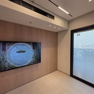 חדר עם מסך טלוויזיה וקיר עץ, חלון ודלת זכוכית.