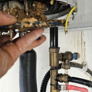 יד מחזיקה חלק מתכת עם חלודה מתחת לדוד שמש