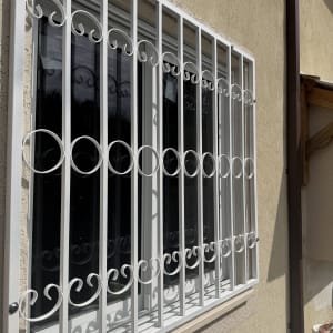 סורגי מתכת לבנים על חלון קיר חיצוני