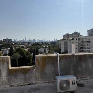 יחידת מיזוג אוויר על גג עם נוף עירוני ברקע