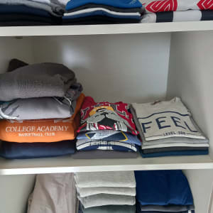 בגדים מקופלים ומסודרים על מדפים בארון