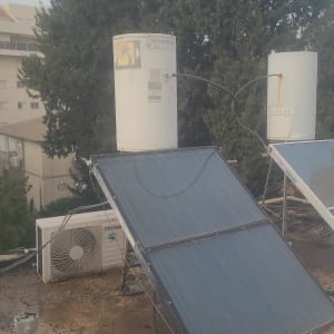 דוד שמש וקולטים על גג עם עצים ברקע