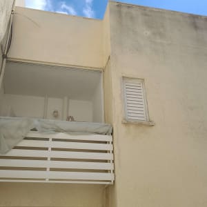 מרפסת עם מעקה לבן ותריסים סגורים