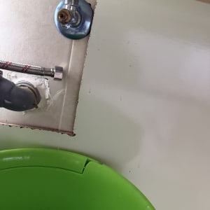 צינור מים וברז מתחת לכיור עם דלי ירוק