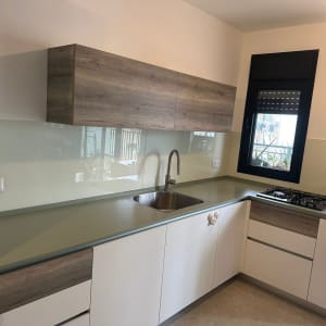 מטבח עם חיפוי זכוכית מעל השיש והכיור