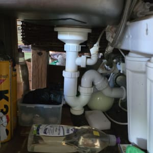 צנרת מתחת לכיור עם בקבוקי ניקוי