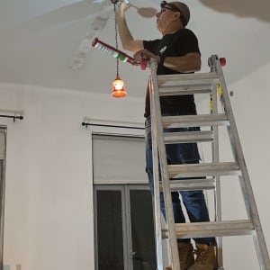 אדם על סולם מתקין תאורה בתקרה