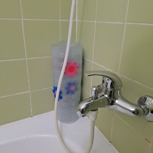 ברז אמבטיה עם צינור לבן על רקע אריחים ירוקים