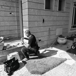 חשמלאי עובד על חוטים ליד קיר חיצוני