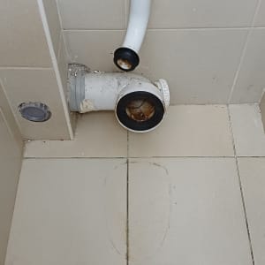 צינור ביוב וחיבורים על רצפת אריחים