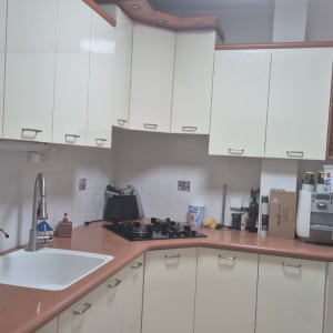 מטבח עם ארונות לבנים, כיור וברז, כיריים ותנור