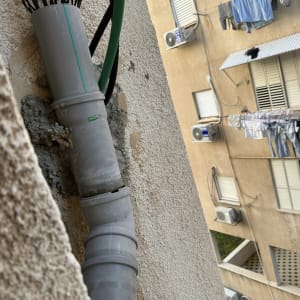 צינור פלסטיק מותקן על קיר חיצוני של בניין