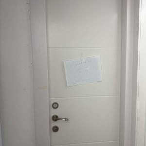 דלת לבנה עם ידית מתכת ודף נייר מודבק