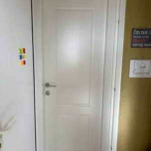 דלת לבנה עם ידית כסופה במסגרת לבנה