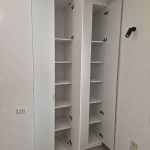 ארון לבן עם דלתות פתוחות ומדפים פנימיים
