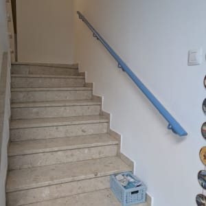 מדרגות עם מעקה כחול וסלסלה על המדרגה התחתונה