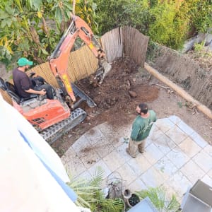 עבודת חפירה בגינה עם מחפרון ועובד