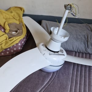 מאוורר תקרה מפורק עם חוטי חשמל חשופים על מיטה