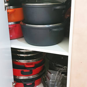 סירים ומחבתות מאורגנים בארון מטבח פתוח