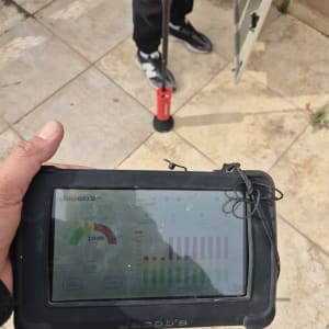 מכשיר מדידה דיגיטלי עם גרפים, אדם מחזיק מוט.