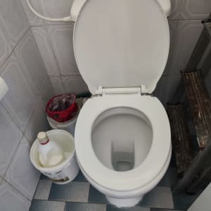 אסלה עומדת לבנה עם ניאגרה גלויה בחדר שירותים מרוצף