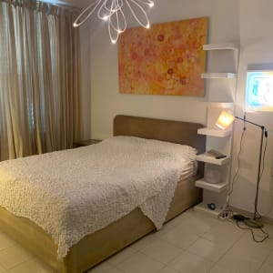 חדר שינה מסודר עם מיטה, מדפים ותאורה מודרנית