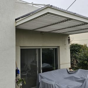 מרפסת עם ריצוף שחור לבן, שולחן מכוסה, צמחייה בצד.