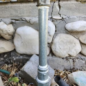 צינור מתכת מחובר לקיר עם אבנים