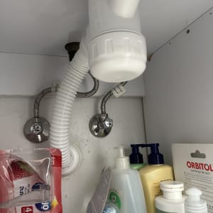 צנרת מתחת לכיור עם מוצרי ניקוי