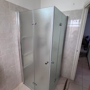 מקלחון זכוכית עם דלתות מתכת בחדר אמבטיה