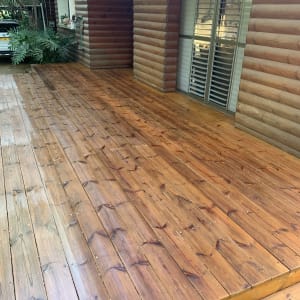 דק עץ חום ליד בית עץ עם חלונות תריסים