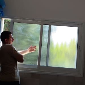 אדם פותח חלון זכוכית בחדר אמבטיה