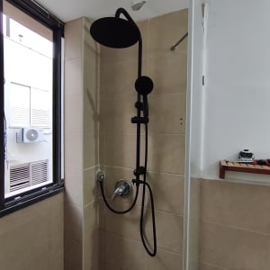 מקלחת עם ראש מקלחת שחור על קיר אריחים