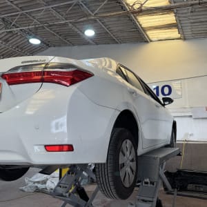 רכב לבן על מעלית במוסך עם שלט מוקד הרכב חיפה