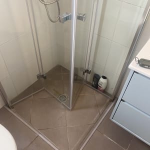 מקלחון זכוכית עם רצפת אריחים וחומרי ניקוי