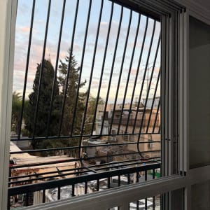 חלון עם סורגים נוף חיצוני של בניינים ועצים