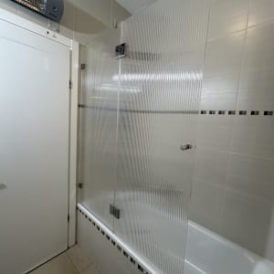 מקלחון עם דלת זכוכית מחוספסת על אמבטיה