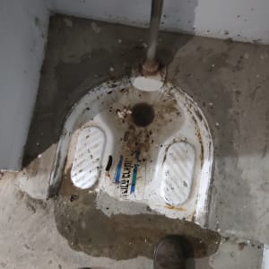 אסלה מזרחית עם צינור מים וחלודה