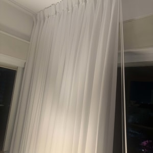 וילון לבן תלוי על מסילה עם יד מושכת חוט