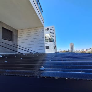 גג מתכת עם ברגים ומבנה בטון בצד