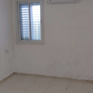 מזגן מותקן על קיר בחדר ריק עם חלון ותאורה