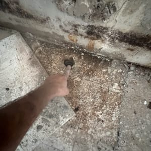 יד מצביעה על חור בקיר עם סימני רטיבות