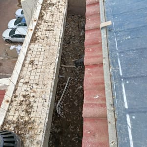 גג עם רעפים אדומים ולכלוך על המרזב